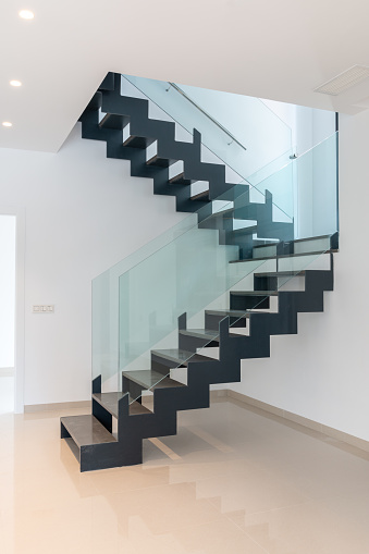 A modern staircase. Openwork stairs made of metal and marble, and glass balustrades.