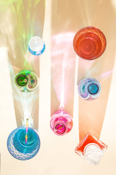 istock Colorful bottles with cold drinks on sandy background. Shadows with shiny colorized reflections. Aesthetic abstract design idea. Sunny beach day concept. 1398544784
