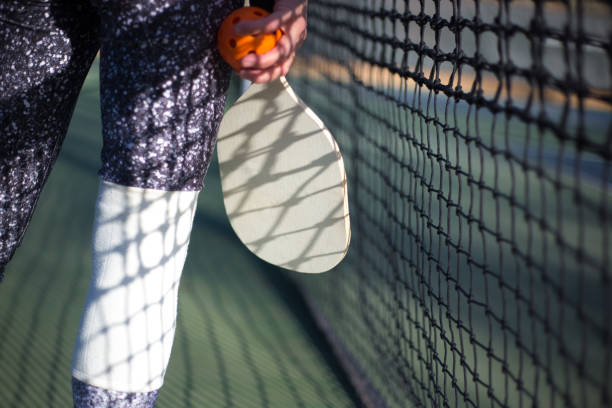 istock Pickleball and Paddle in Woman's Hand Close-Up, Net in Background 1398547027