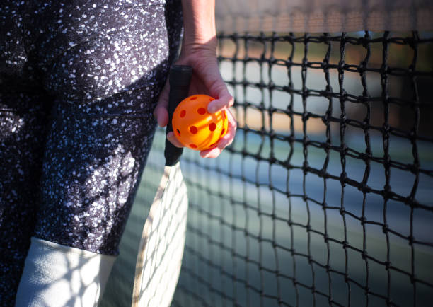 istock Pickleball and Paddle in Woman's Hand Close-Up, Net in Background 1398547037
