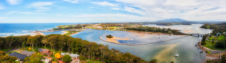 Aerial panorama over Narooma town river inlet on the South Coast of NSW, Australia - aquaculture oyster fishing farms.