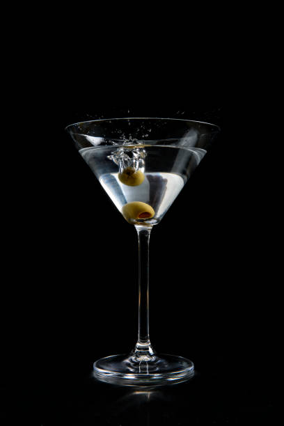 オリーブが飛び散る黒い背景のマティーニガラスの正面図 - martini royale ストックフォトと画像