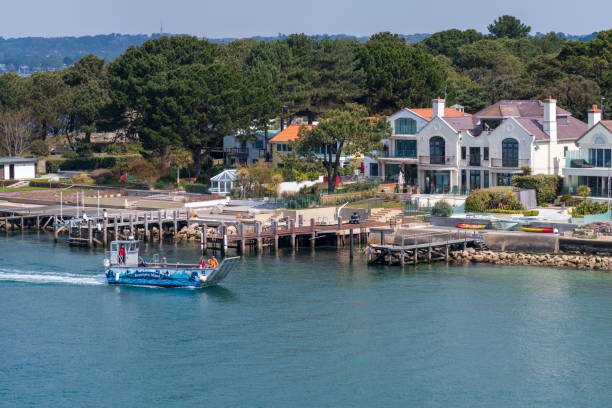 Sandbanks, United Kingdom - April 29, 2022: Blue boat passing by Sandbanks Houses
