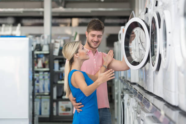 Beautiful Young Couple Shopping Washing Machine In Supermarket stock photo