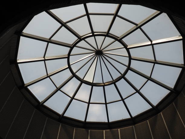 cúpula de vidrio o ventana redonda en el techo. el cielo se puede ver a través de una estructura transparente de vidrio en la bóveda del edificio. motivos arquitectónicos de moda en la construcción moderna. una gran ventana redonda - dome skylight stained glass glass fotografías e imágenes de stock