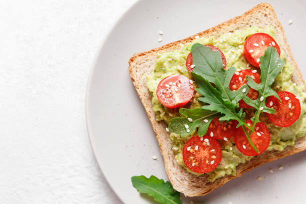 istock Avocado rye bread toast with cherry tomatoes and arugula on bright background. Healthy appetizer, breakfast, lunch or snack. Vegan food concept. Close up, top view 1398553851