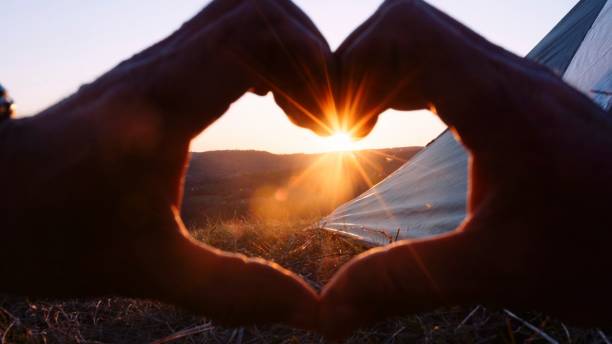 Mountain biker playing with the sun in front of gorgeous sunset. Vacations with bicycle and tent.
