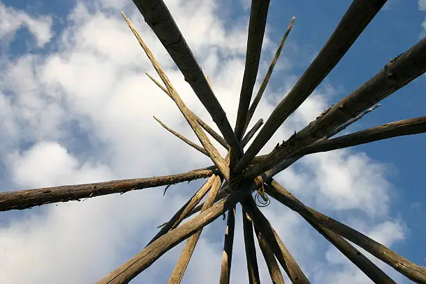 Top of a tepee looking up into the blue sky.