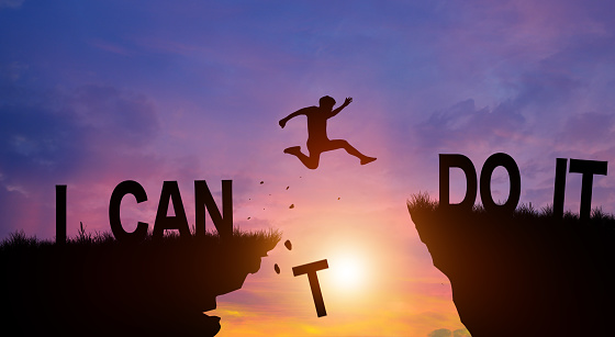 Silhouette man jumping over the cliffs with I can do it word in sunlight. Never give up, Good mindset Concept.