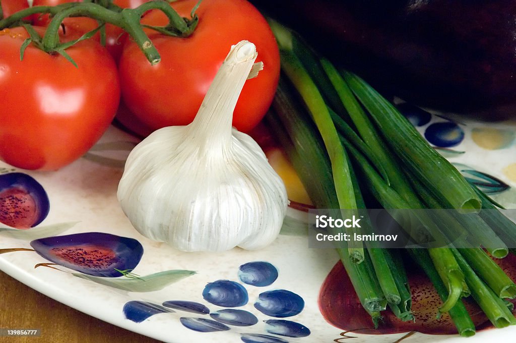 Pomodori, aglio e cipollotti su un piatto. - Foto stock royalty-free di Aglio - Alliacee