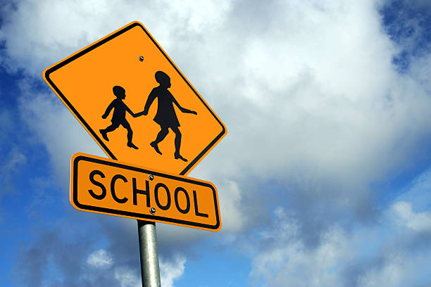 A yellow sign warning of a school zone stock photo