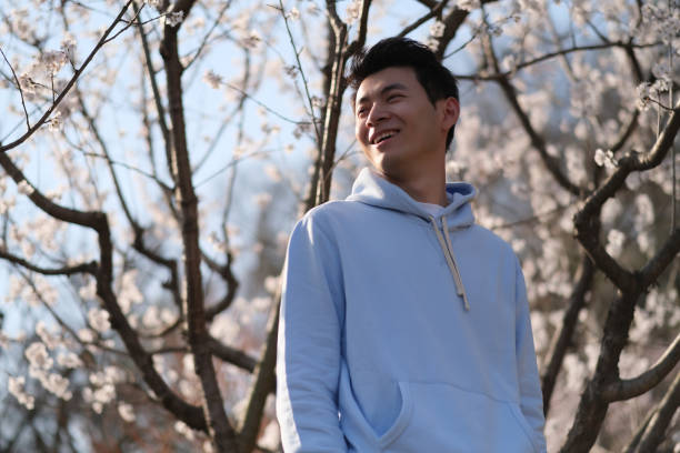 istock happy smiling Asian young under sakura blossom tree 1398571473