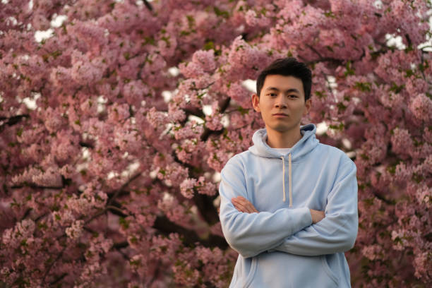istock cool handsome Asian young man at pink sakura tree 1398571474