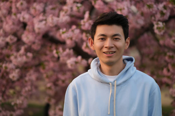 istock cute Asian young man smiling. pink sakura flowers 1398571499