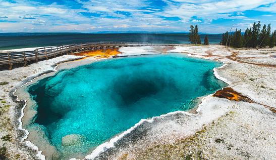 Bright blue clear hot spring with caves and blue sky at Yellowstone national park.