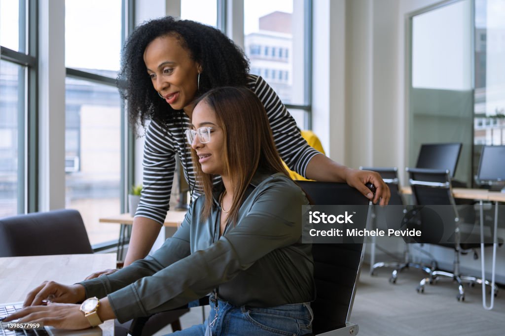 Woman mentoring a young employee in the office Mentorship Stock Photo