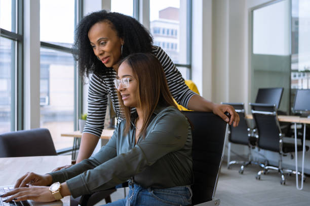 Woman mentoring a young employee in the office Woman mentoring a young employee in the office mentorship stock pictures, royalty-free photos & images