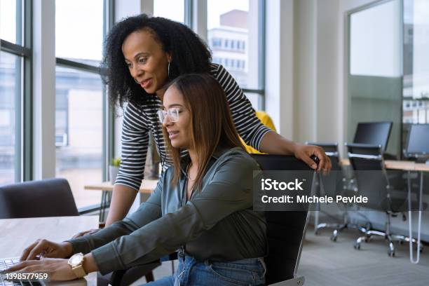 Woman Mentoring A Young Employee In The Office Stock Photo - Download Image Now - Mentorship, Advice, Instructor