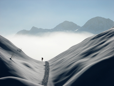 Ski mountaineering or cross country skiing in Slovenia, Komna area, silhouette of a man coming out from clouds