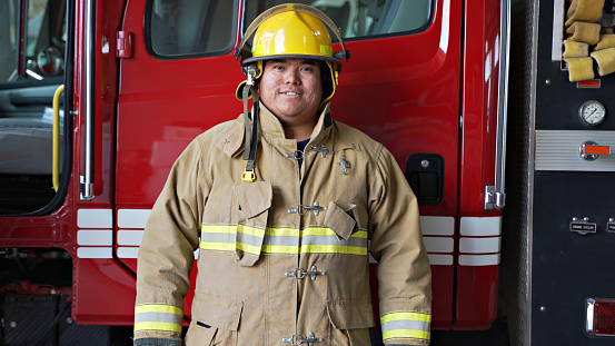 Firefighter with work helmet under arm looking at camera
