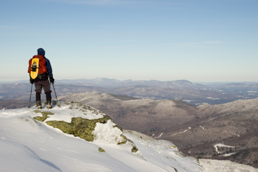 Backpacker/hiker standing at the top of Mt. Mansfield Vermont taking in the view.