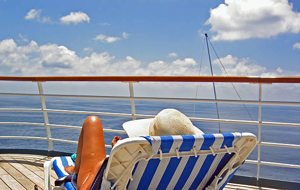 View from the Cruise Deck A woman sits on a lounge chair and overlooks the ocean from a cruise ship cruise ship people stock pictures, royalty-free photos & images