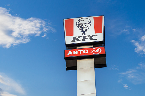 Krasnoyarsk, Russia - May 19, 2022: KFC restaurant logo with KFC Drive and open 24 hours on blue sky. KFC is a fast food restaurant chain that specializes in fried chicken. Fried chicken fast food