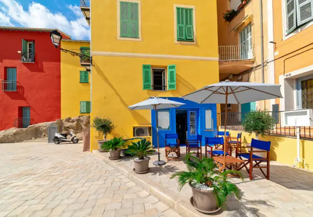 Small outdoor restaurant and colorful houses in Menton, France.