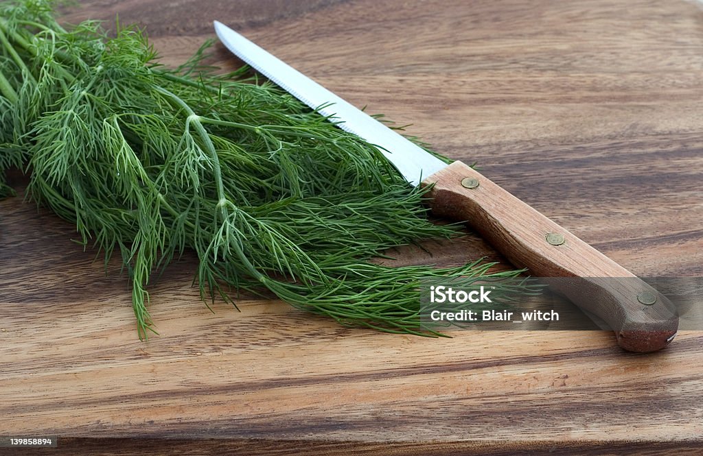 dill and knife on a cutting board fresh dill and knife on a wooden cutting board Awe Stock Photo