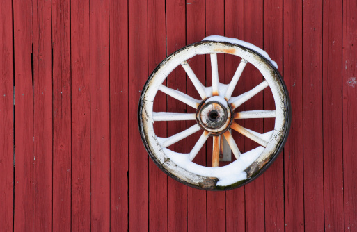 Wooden whell on red barn wall