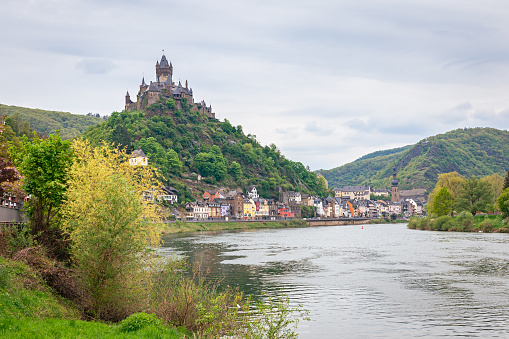 Cochem, Germany - May 2022: Picturesque view of a castle on a hill near the historic town of Cochem along the river Moselle in Germany.