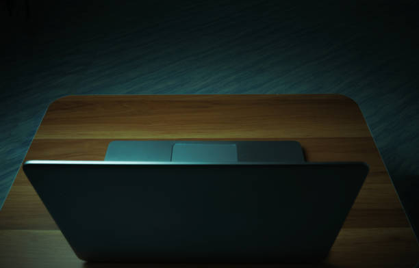 灰色のラップトップは、ライトが点灯した暗い部屋の木製のテーブルの上に置かれました。コンセプトインターネット addiction.top ビュー。 - internet addiction pornography computer ストックフォトと画像