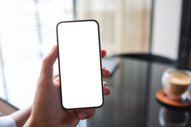 istock Mockup image of a man holding mobile phone with blank white screen with coffee cup on the table 1398591790