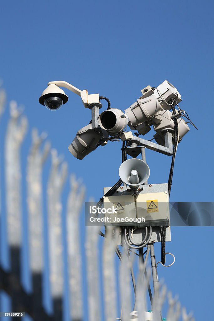 Watching High-tech security monitoring with soft-focus pallisade fencing in foreground Activity Stock Photo