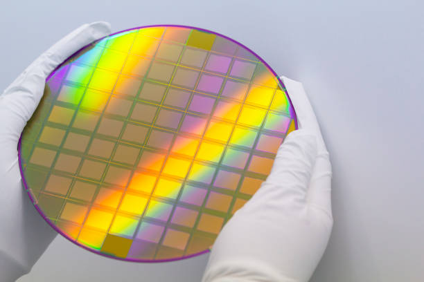 istock Hands in white gloves holding a silicon wafer with microchips on white background.Banner format. 1398597826