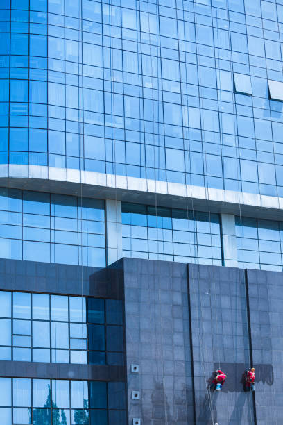 istock Man washing washing office building windows while hanging from r 1398599314