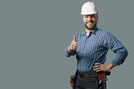 Smiling engineer with safety helmet, he is giving a thumbs up, professional service concept
