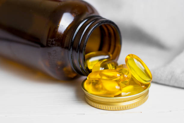 Yellow capsules, tablets, fish oil pills, a brown glass jar lie on a white table. Vitamin complex omega 3,6,9. Fish oil capsules with omega-3, vitamin D in a glass bottle on fabric cápsulas amarillas, tabletas, píldoras de aceite de pescado, un frasco de vidrio marrón se encuentran sobre una mesa blanca. complejo vitamínico omega 3,6,9. cápsulas de aceite de pescado con omega-3, vitamina d en una botella de vidrio sobre tela