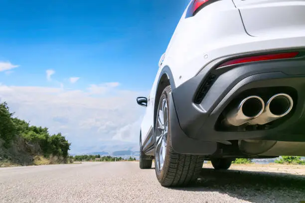 Bottom view of wheel and pipe of white car driving on the meandering serpentine countryside road in the mountain.