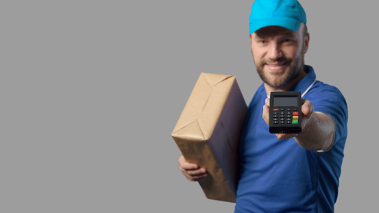 Professional delivery man holding a box and a POS terminal