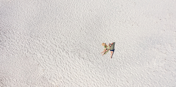 Aerial view of a young couple lying on the white sand. man and woman spend time together and travel through the desert.