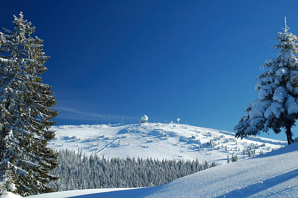 Winter scene La Dole, a Swiss mountain with a radar installation at its summit, in winter. Skiers and their tracks can be seen on the mountainside as this is also a ski resort. jura france stock pictures, royalty-free photos & images