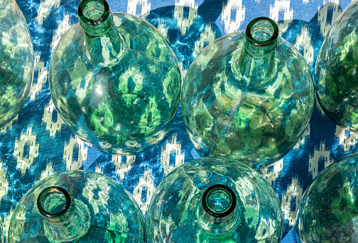 Green glass bottles typical of the culture of the island of Mallorca, displayed in a street market on white and blue fabrics