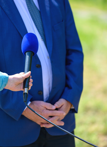 A female journalist with a microphone interviewing a businessman