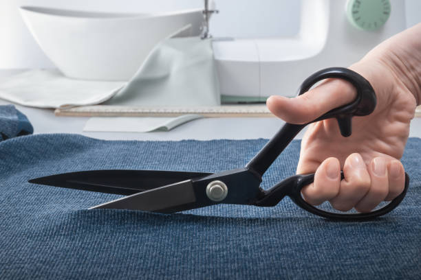 istock Tailor's scissors in a woman's hand cut the fabric. Close-up 1398618241