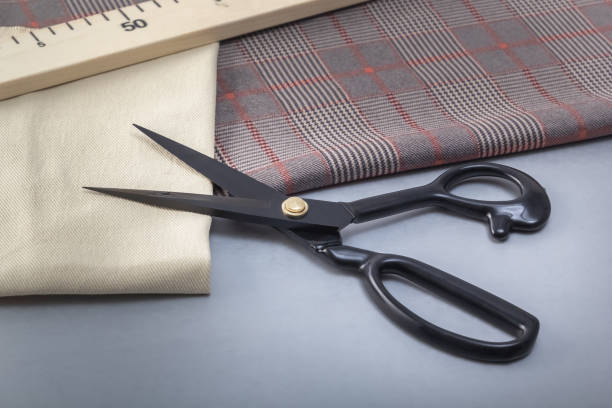 istock Open tailor's scissors lie with a wooden meter on cuts of material. Close-up 1398618326