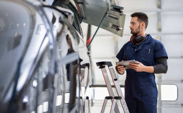 istock Male Aero Engineer With Clipboard Checking On Helicopter In Hangar 1398620451