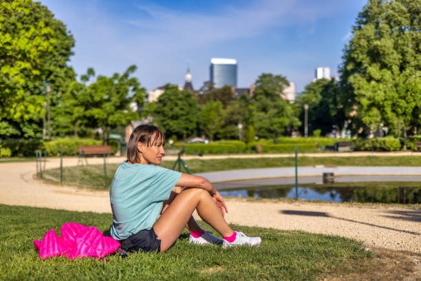 Sportive young woman sitting and resting in a public part of an eco urban area of the city stock photo