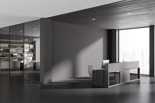 Dark reception room interior with desk and pc computer, side view, manager room behind glass doors. Panoramic window on city view, grey concrete floor. Mockup empty wall. 3D rendering