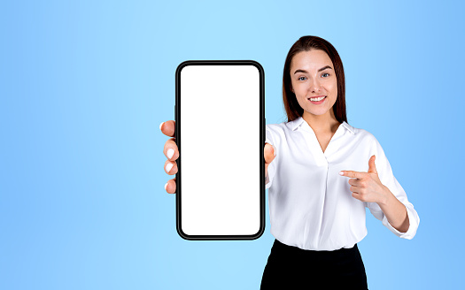 Businesswoman showing smartphone, finger point at mock up copy space screen on blue background. Concept of website and social media